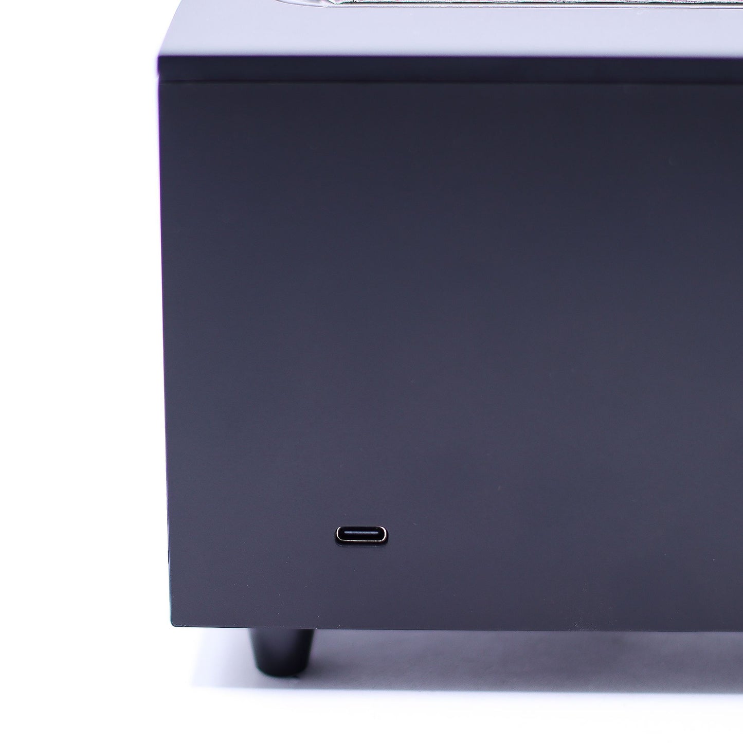 Dark gray rectangular electronics enclosure shows a USB-C port centered near its lower front face, sitting on small black feet against a white background.