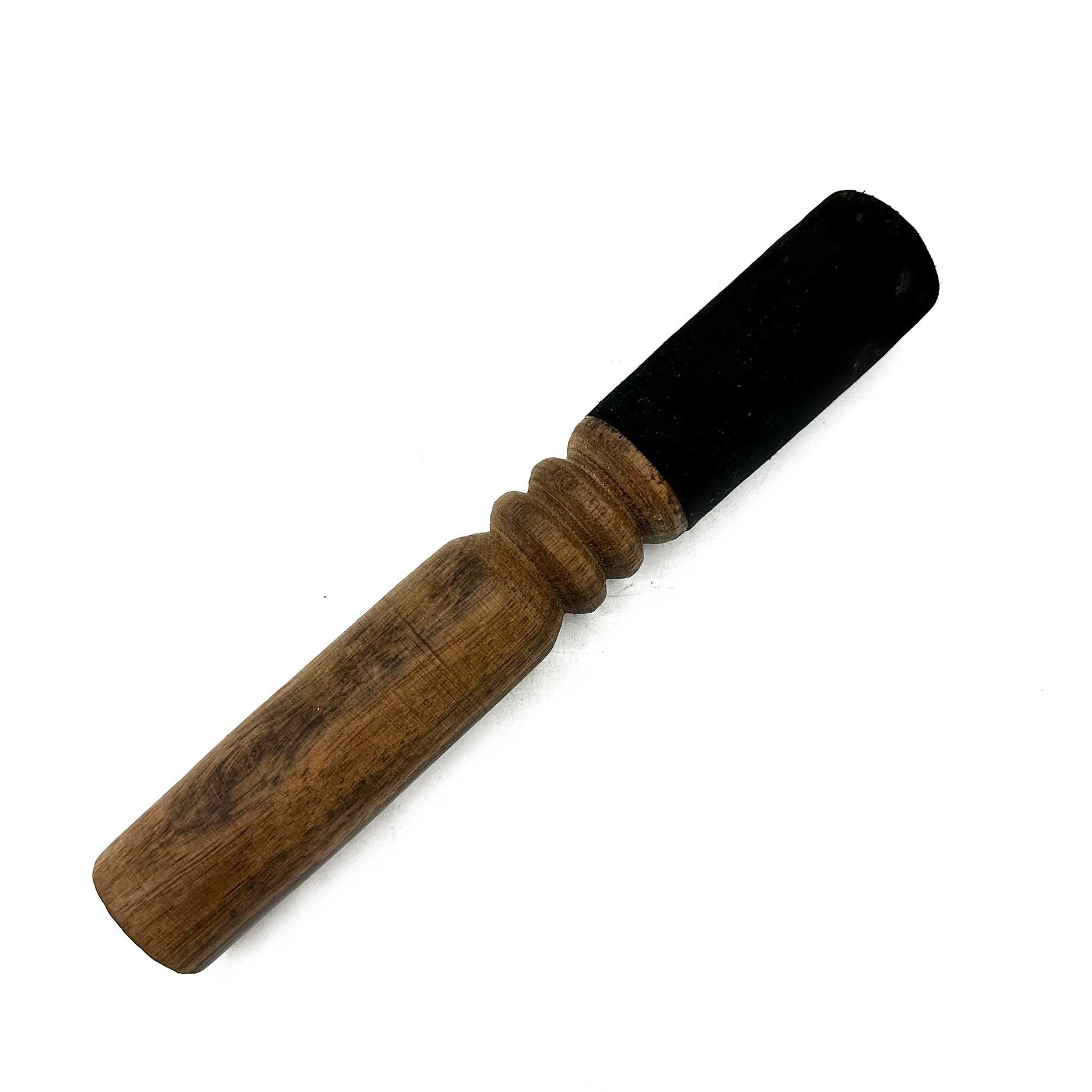 Wooden rod with a black rubber cap lies diagonally on a white background, worn brown turned-wood shaft showing three rounded rings near the capped end.