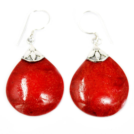 Pair of red teardrop earrings hanging from silver hook findings, showing glossy textured coral like surfaces and small silver floral caps against a plain white background.