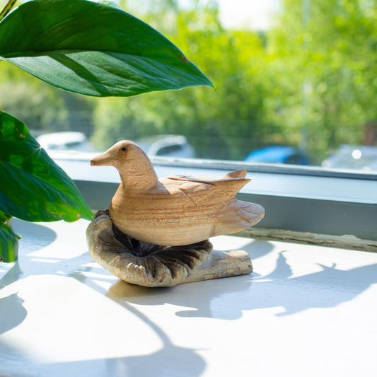 Hand-carved wooden duck ornament resting on natural parasite wood base UK