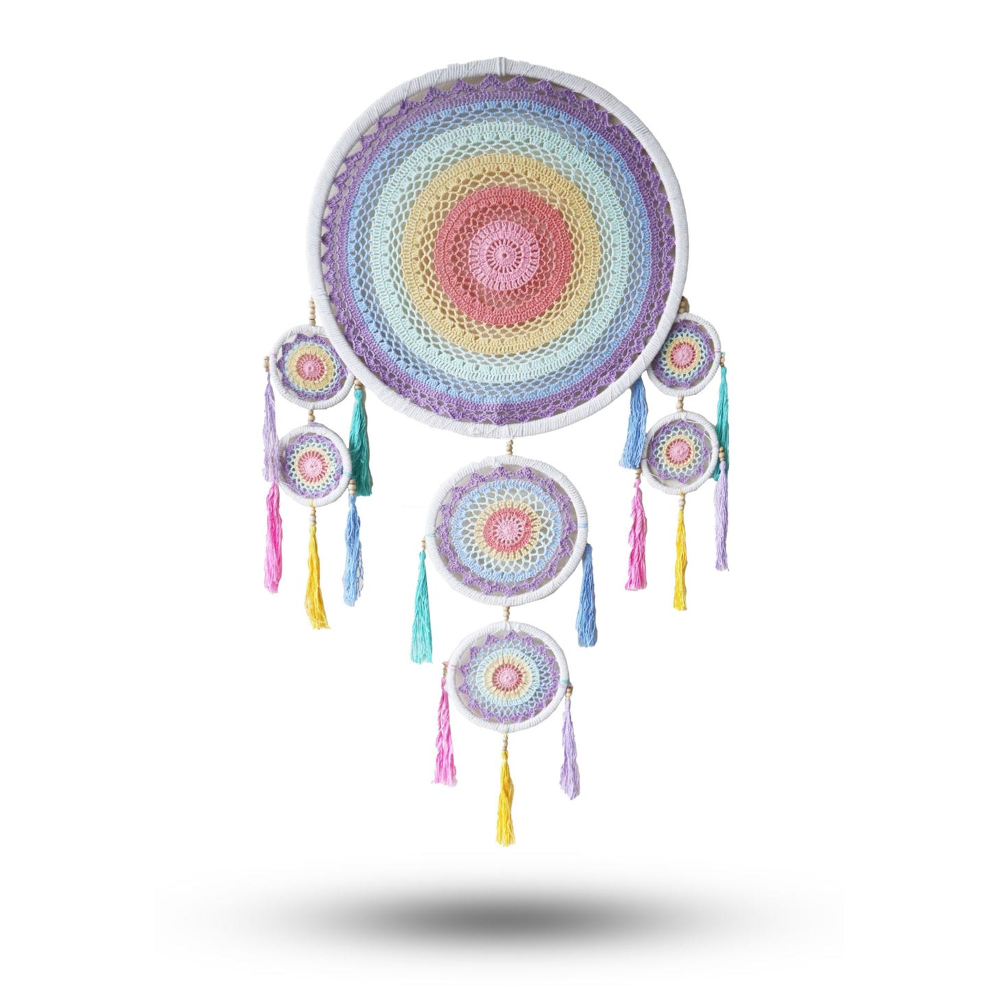 Crocheted dreamcatcher hangs showcasing concentric pastel mandalas with dangling smaller hoops and multicolored tassels against a plain white background.