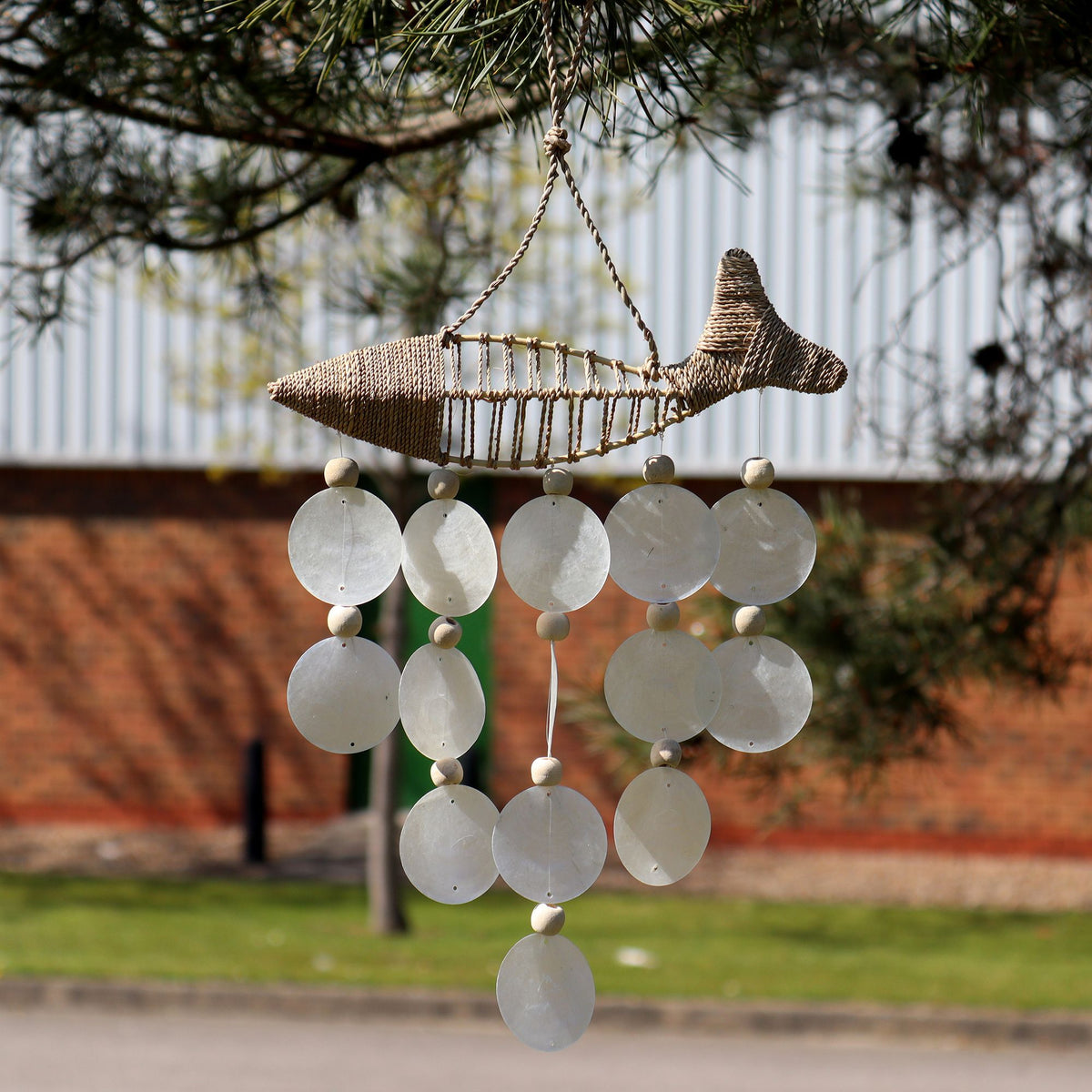 Handmade woven string fish windchime with natural Capiz shell drops.