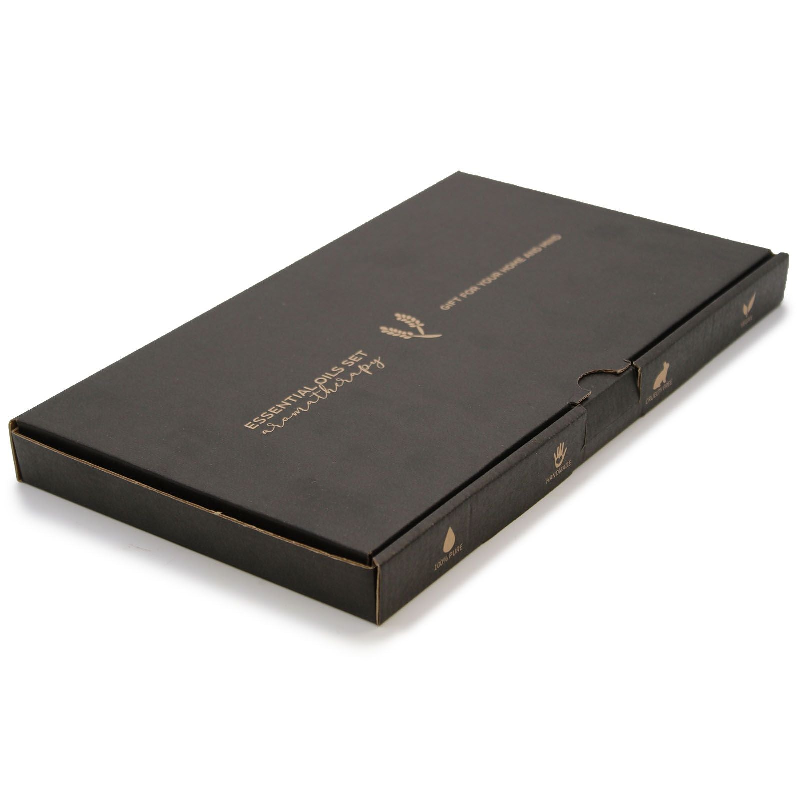 Black rectangular essential oils box rests angled on a white surface; gold text reads ESSENTIAL OILS SET aromatherapy and side labels 100% PURE HANDMADE CRUELTY FREE.