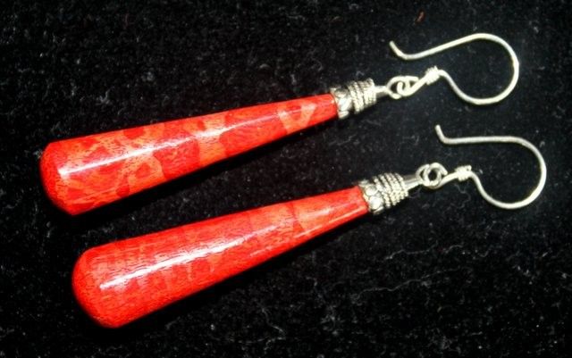 Pair of elongated red teardrop earrings with silver caps and fishhook wires lie side by side on a black velvet background, the glossy crackled finish reflecting light.