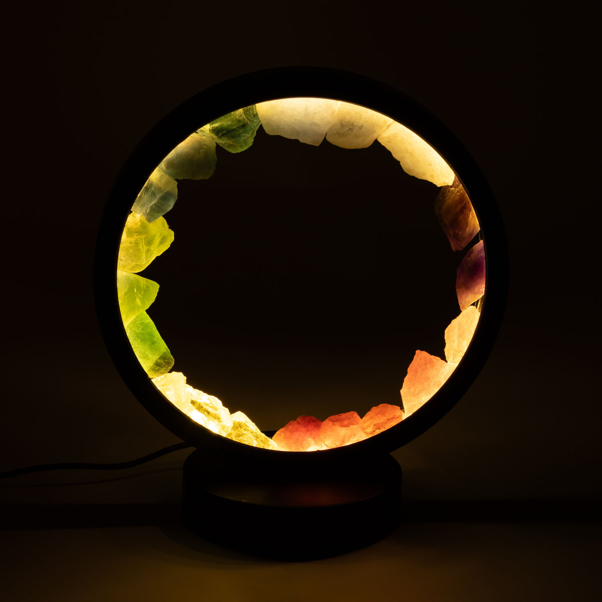 7 Chakra Gemstone Halo Lamp with seven coloured natural gemstone sections glowing on black metal stand UK