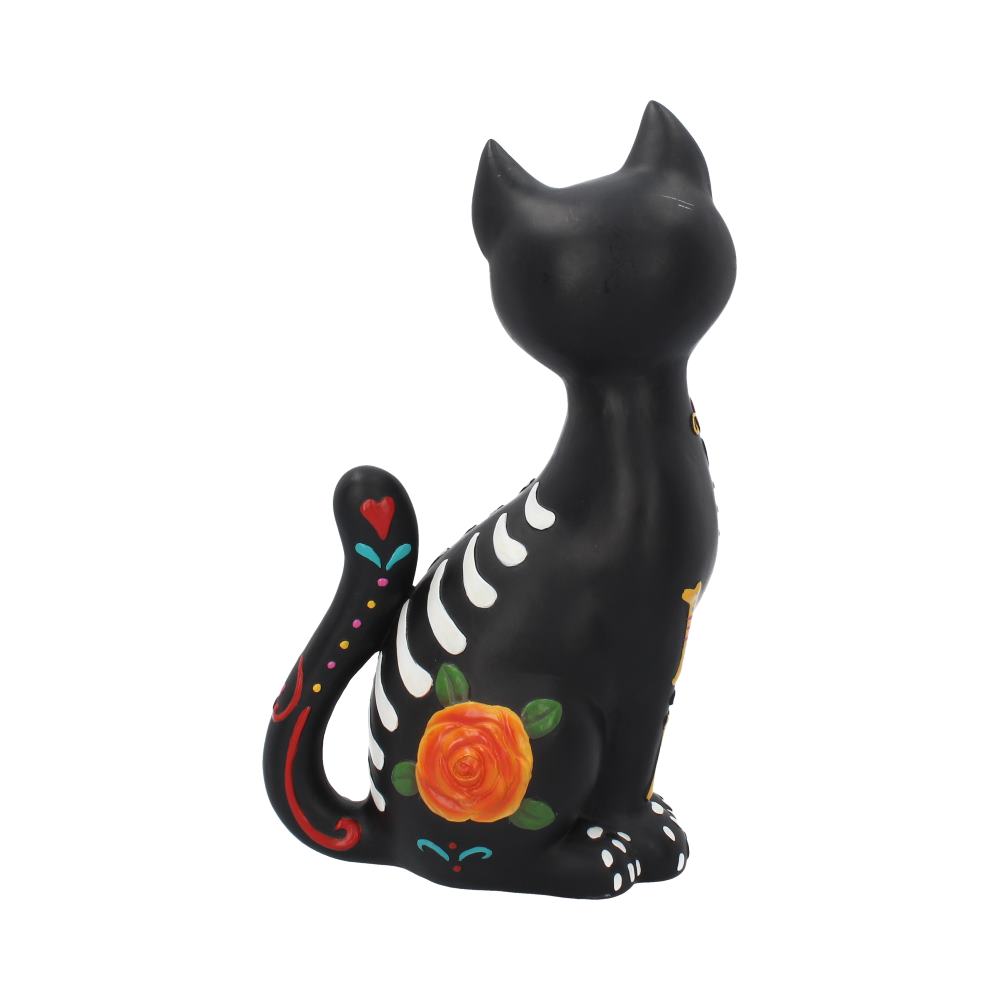 A black ceramic cat figurine is decorated with white skeletal patterns and colorful floral designs, including a prominent orange flower. It sits gracefully, displaying festive, Day of the Dead-inspired artwork.