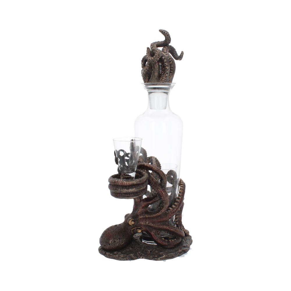 A clear glass liquor decanter sits cradled in a brown, sculpted octopus holder with tentacles; two shot glasses are held by the octopus, on a white background.