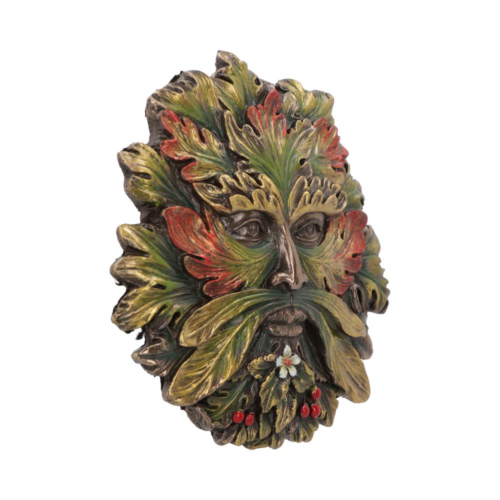 A decorative mask features a face composed of autumn-colored leaves and foliage, with red and green hues. It is set in a plain, white background, enhancing its intricate details.