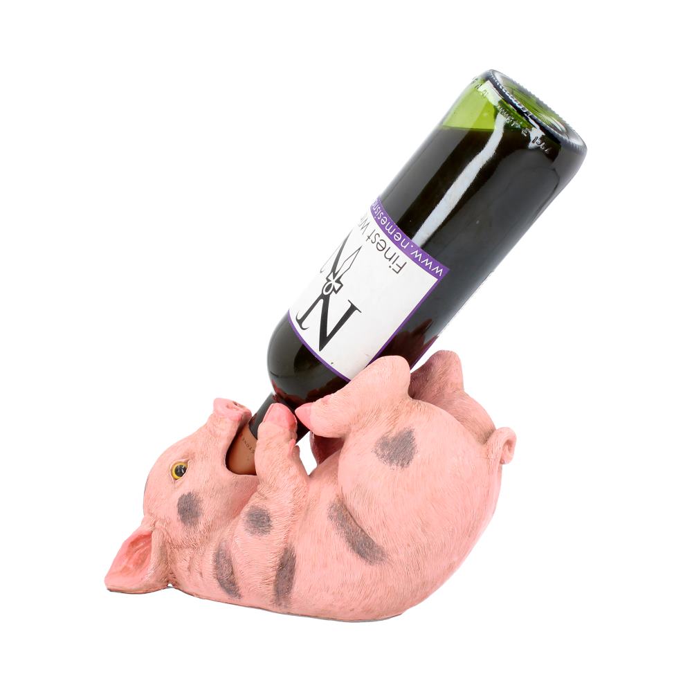 A pig-shaped wine holder lies on its back, gripping a wine bottle with all limbs. The label on the bottle reads "Finch Winery" and "WWW.DOSSIGNS.CO.UK."