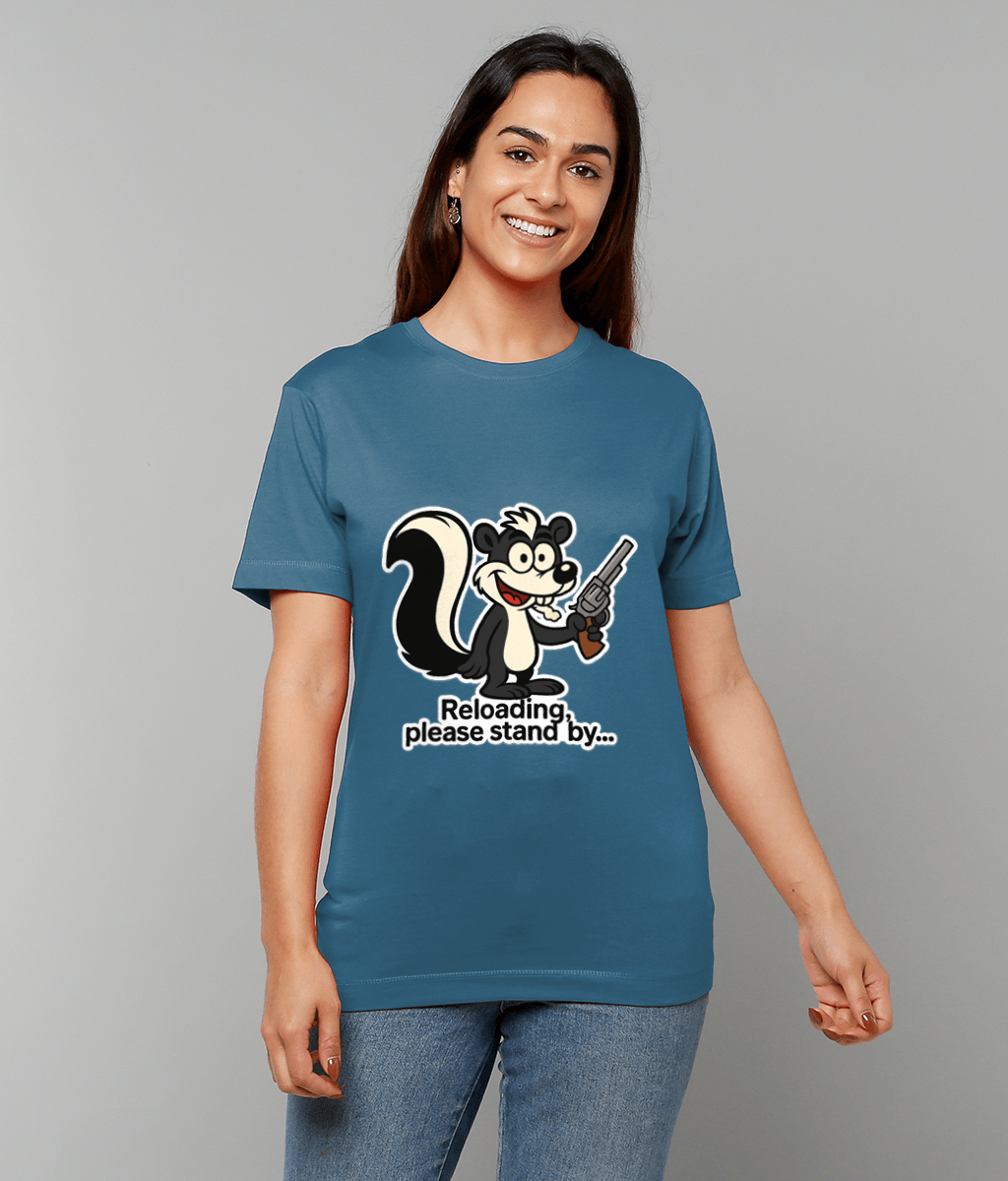 Cartoon skunk holding a revolver and grinning printed on a blue T-shirt worn by a smiling woman against a plain gray background, text reads: Reloading, please stand by...