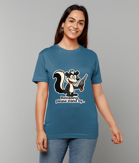 Cartoon skunk holding a revolver and grinning printed on a blue T-shirt worn by a smiling woman against a plain gray background, text reads: Reloading, please stand by...