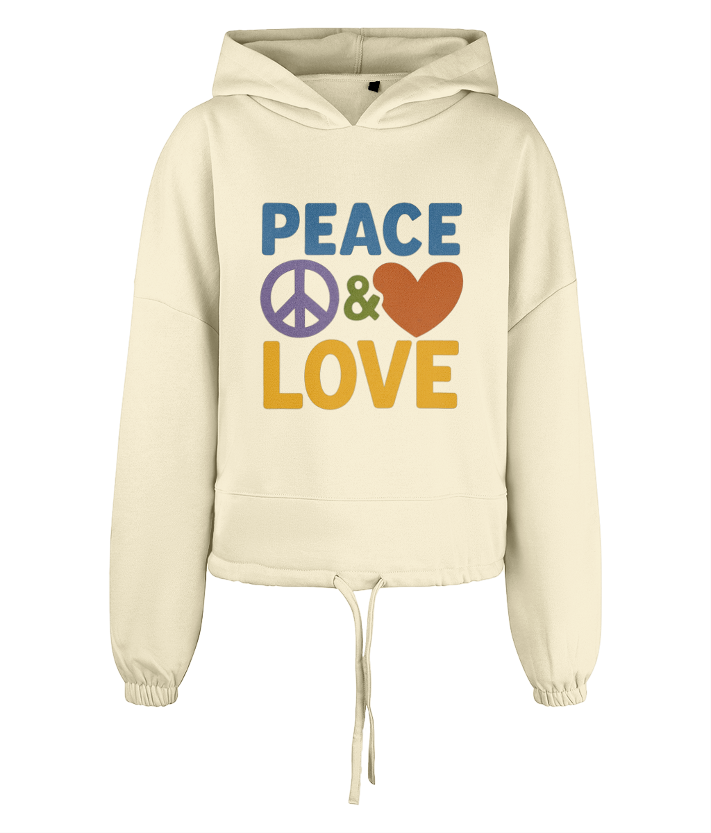 Cream cropped hoodie displays PEACE ☮ & ♥ LOVE printed in bold colorful letters across the front, centered on the garment against a plain black background.