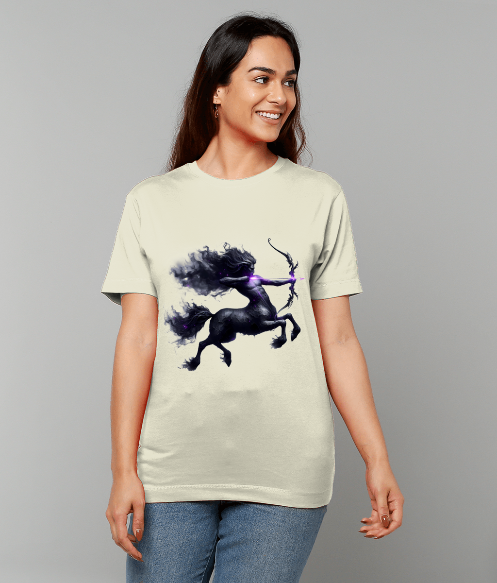 A dark ethereal centaur archer draws a glowing purple bow printed on a cream T-shirt worn by a smiling woman standing against a plain light gray studio backdrop.
