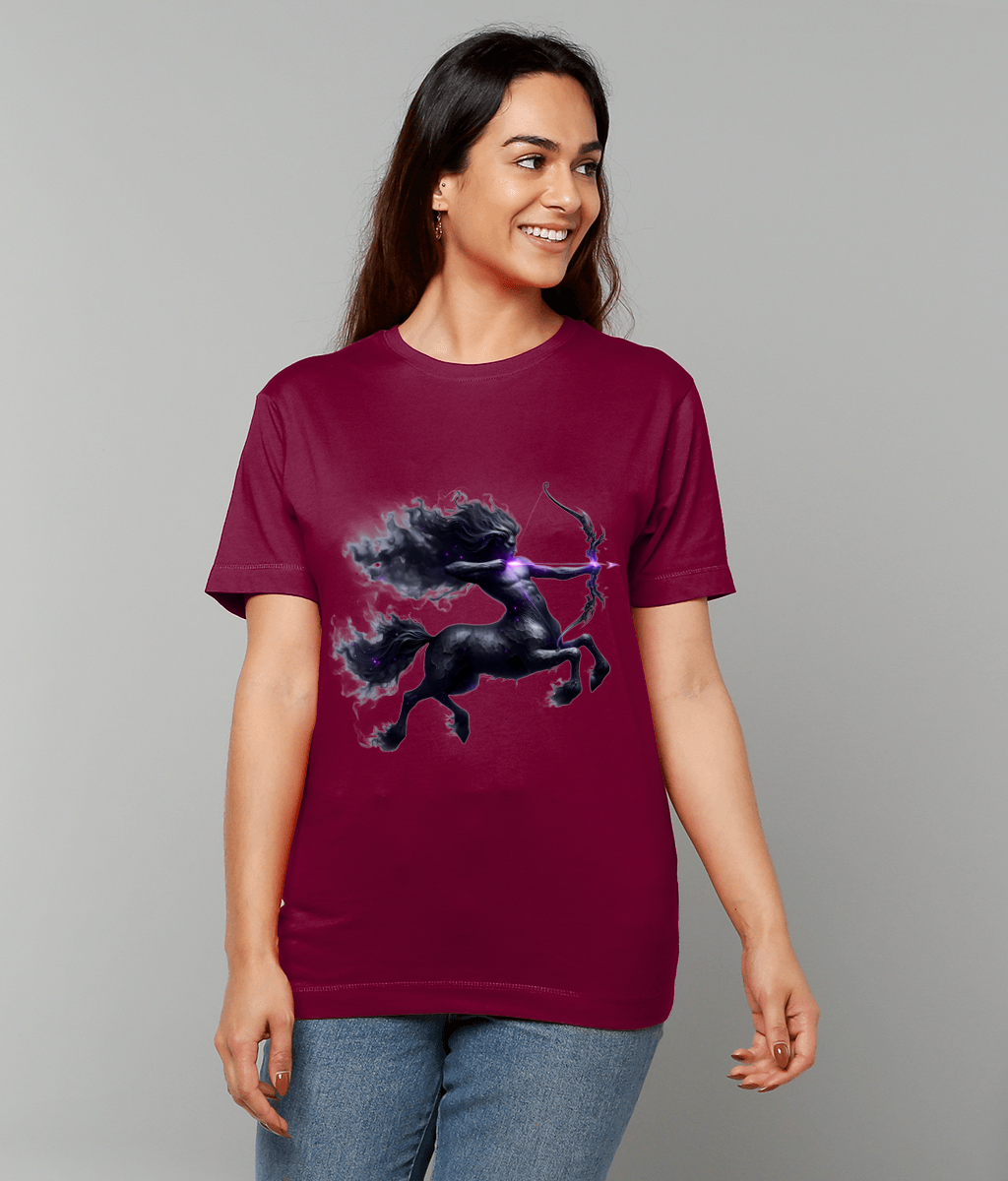 Maroon T-shirt displaying a smoky black centaur drawing a glowing bow worn by a smiling woman standing against a plain light gray background.