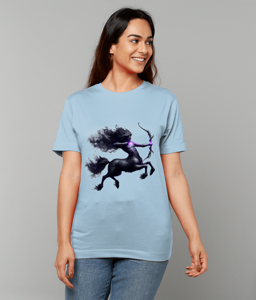 A woman wears a light-blue T-shirt featuring a dark, smoky centaur archer pulling a glowing purple arrow on a bow while posing against a plain gray studio background.