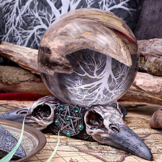 A crystal ball, filled with a tree image, rests atop two raven skulls conjoined by a pentacle. Skulls' text: "For one so brave," "If I flame the." The scene is on a map.