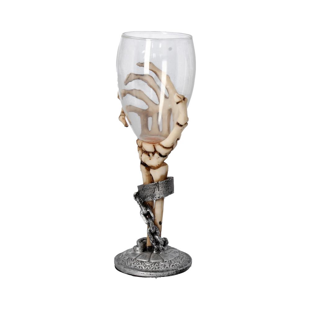 A wine glass is clasped by a skeletal hand, complete with a chain and band around the "wrist," atop an ornate silver base, against a white background.