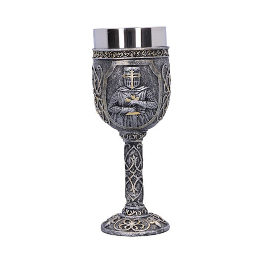 A decorative silver goblet stands on a white surface. It's detailed with a medieval knight figure, and the stem and base have intricate designs.