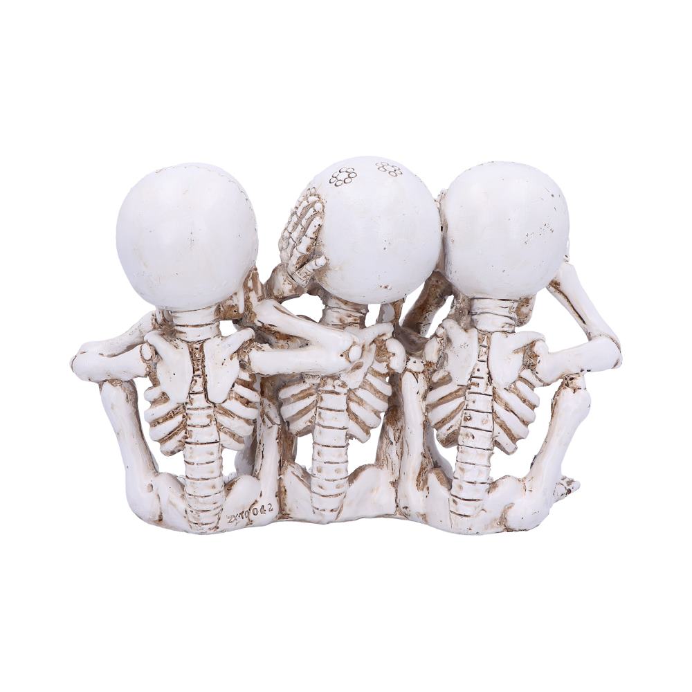 Three small skeleton figurines sit side by side, each covering their eyes, ears, and mouth with their hands, respectively. They form a "see no evil, hear no evil, speak no evil" display.