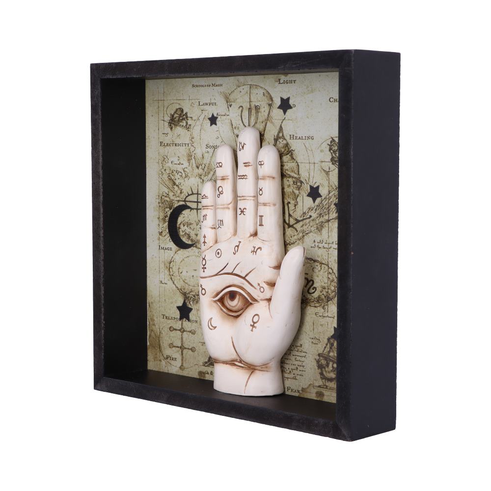 A decorative, sculpted hand with an eye on the palm stands in a black-framed shadow box. The background is a vintage-style map with text that includes: "SCHOOLS OF MAGIC," "LIGHT," "HEALING," and "FIRE."