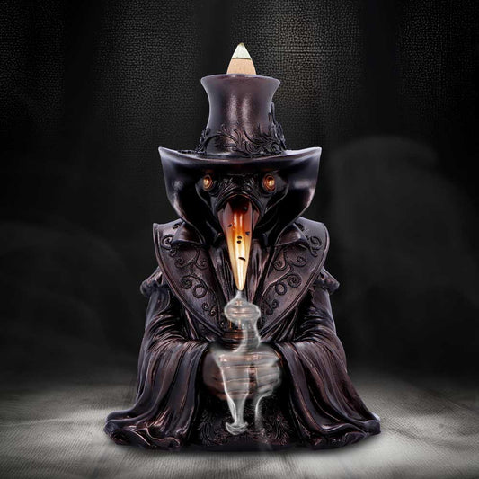 A dark resin plague doctor statue with top hat and long beak holds a smoking vial, smoke curling upward as it sits on a textured surface against a smoky backdrop.