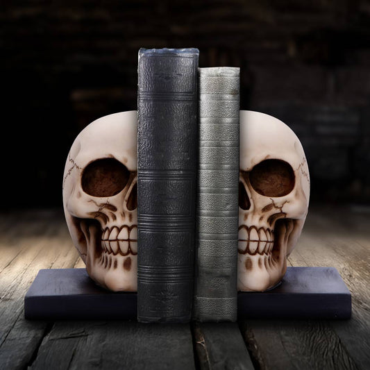 Two skulls flank and support two upright leather-bound books resting on a wooden plank in a dim, rustic room with a worn wooden floor and dark blurred background.